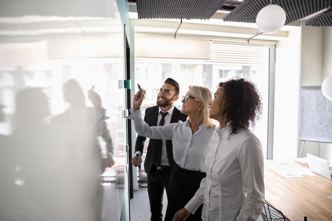 Motivated diverse employees brainstorm develop strategies on whiteboard